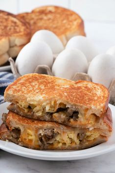 two sandwiches stacked on top of each other with eggs in the backgroung