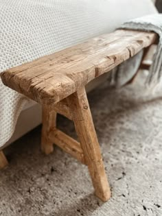 a wooden bench sitting on top of a bed next to a white pillow with the words diy rustic bench