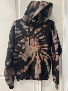 a black and brown tie dye hoodie hanging on a door