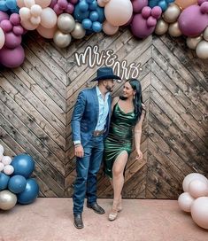 a man and woman standing next to each other in front of balloons