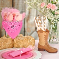 the table is set with pink and brown decorations, straw bales, cowboy boots, and baby's breath flowers