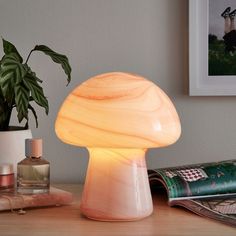 a mushroom shaped lamp sitting on top of a wooden table next to a potted plant