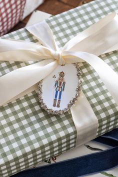 a gift wrapped in green and white checkered paper with an ornament on it