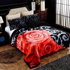 a black and red comforter with a rose on it in the middle of a room