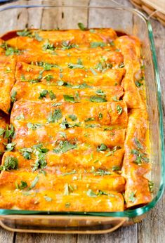 a casserole dish filled with cheese and green garnish on top of a wooden table