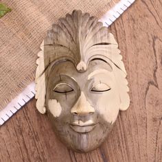 a wooden mask with eyes closed on top of a table