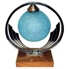 a blue glass ball sitting on top of a wooden base with metal trim around it