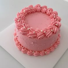 a pink frosted cake sitting on top of a white plate