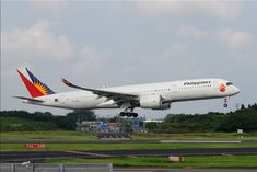 an airplane is taking off from the runway in front of some trees and grass on a cloudy day