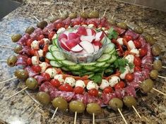 a platter filled with cucumbers, olives and meat on skewers