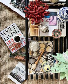 there are many books and magazines on the table with coffee mugs, vases, and other items