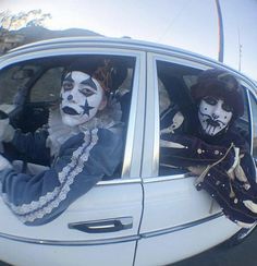 two clowns are sitting in the back seat of a car with their faces painted white