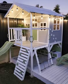 a small house with a slide in the back yard and lights on it's roof