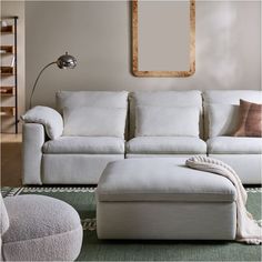 a living room with a white couch and footstool in front of a mirror