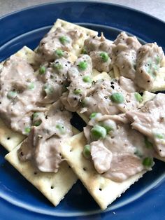 a blue plate topped with crackers covered in meat and peas