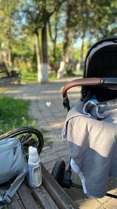 a baby stroller sitting on top of a wooden bench next to a bag and bottle