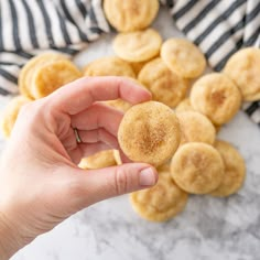 a hand holding a sugary pastry in front of some other pastries on a marble surface