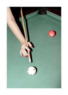 a woman's hand reaching for a pool ball with two cues on it