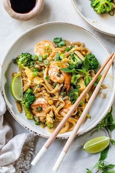 shrimp and broccoli stir fry with chopsticks in a white bowl on a table