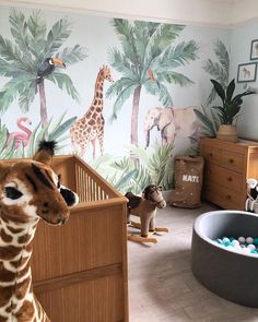 a baby's room with giraffes and zebras painted on the walls