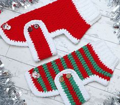 two red and green knitted sweaters sitting next to silver tinsel