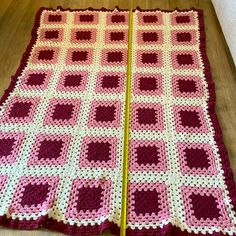 a crocheted blanket is laying on the floor next to a pair of scissors