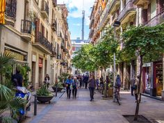 many people are walking down the street in an urban area with tall buildings and trees