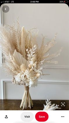 an arrangement of dried flowers in a vase on a table