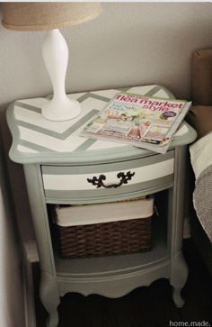 a white lamp sitting on top of a table next to a basket and a magazine