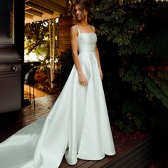 a woman in a white wedding dress standing on a wooden deck next to a piano