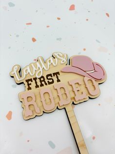 a wooden sign with the words playlist first rodeo on it and a pink hat