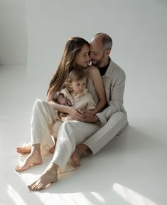 a man, woman and child are sitting on the floor with their arms around each other