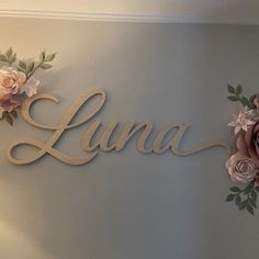 the name luna is made out of wood and has pink flowers on it, along with greenery