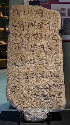 a large rock with writing on it sitting in front of a display case at a museum