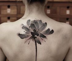 the back of a woman's neck with a black and white flower on it