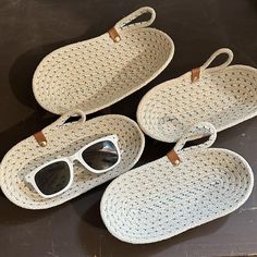 three woven baskets with sunglasses on them sitting on a black table next to each other