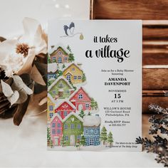 there is a card that says it takes a village with houses and trees on it