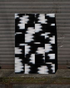 a black and white abstract painting on the side of a building in front of a garage door