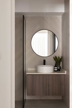 a bathroom with a round mirror above the sink and a plant on the counter top