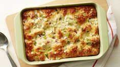 a green casserole dish with meat and cheese in it next to a spoon