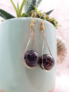 Black and gold colored swirled beads sit in a lovely drop setting. Gold Beaded Teardrop Earrings For Gift, Gold Beaded Earrings With Black Beads For Party, Teardrop Gold Beads Earrings For Party, Gold Teardrop Earrings With Round Beads For Gifts, Handmade Black Teardrop Earrings For Party, Wire Wrapped Teardrop Earrings For Party, Black Beaded Teardrop Earrings For Gift, Teardrop Black Beaded Earrings As Gift, Teardrop Black Beaded Earrings For Gift