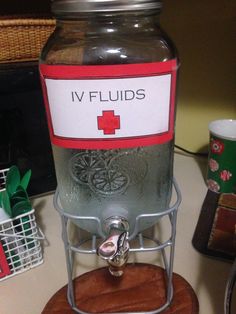 a glass jar filled with liquid sitting on top of a wooden stand next to a cup