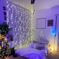 a bedroom decorated for christmas with lights on the wall and bed in front of it