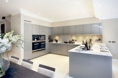 a modern kitchen with stainless steel appliances and marble counter tops, along with white flowers in a vase