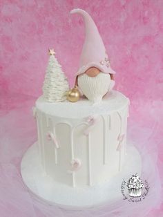 a white cake topped with a gnome and a christmas tree