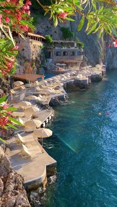 the beach is lined with lounge chairs and umbrellas near the water's edge