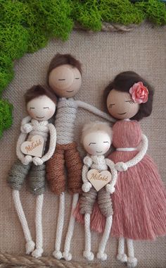 a group of three dolls sitting next to each other on top of a piece of cloth