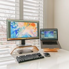 two computers are sitting on a white desk