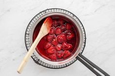 a metal bowl filled with raspberries and a wooden spoon