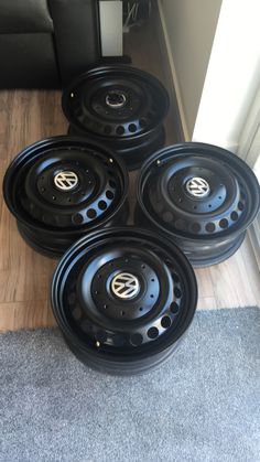 four black rims are sitting on the floor